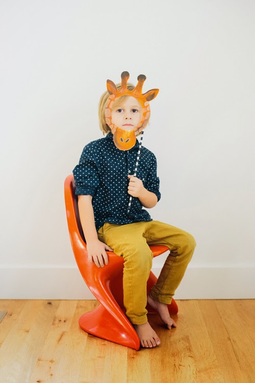 Little boy wears giraffe mask.