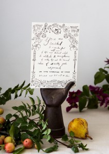 black and white illustrated halloween party invitation in a black decorative hadn surrounded by foliage and fruits