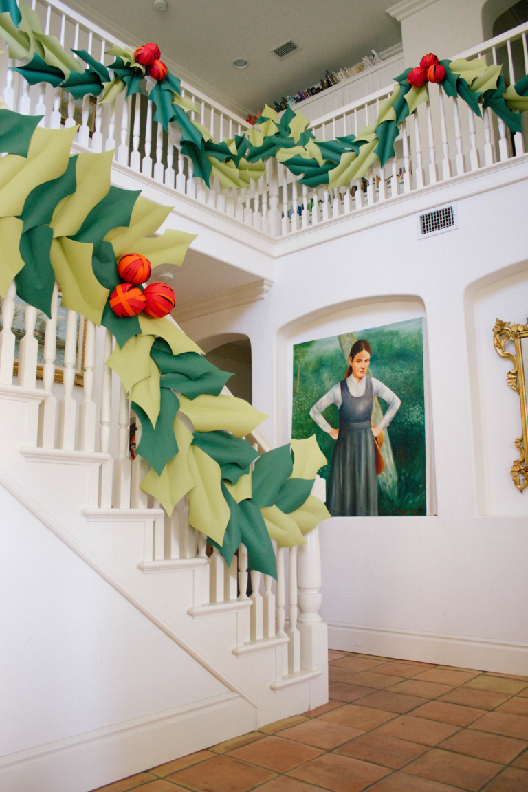 Giant paper holly and paper berries hung around a big banister