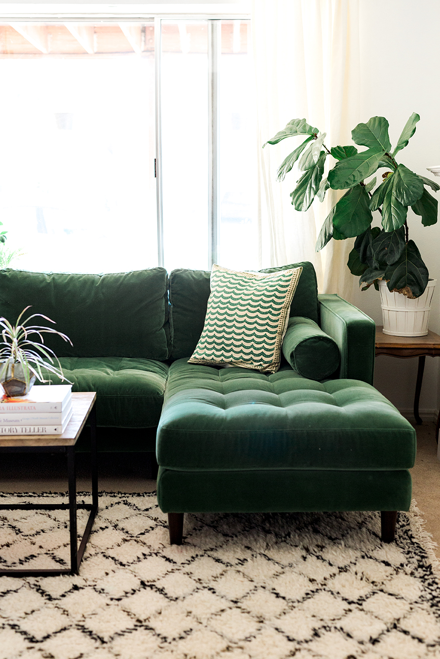 Brittany adjusts pillows on a beautiful green sofa in a light-filled room
