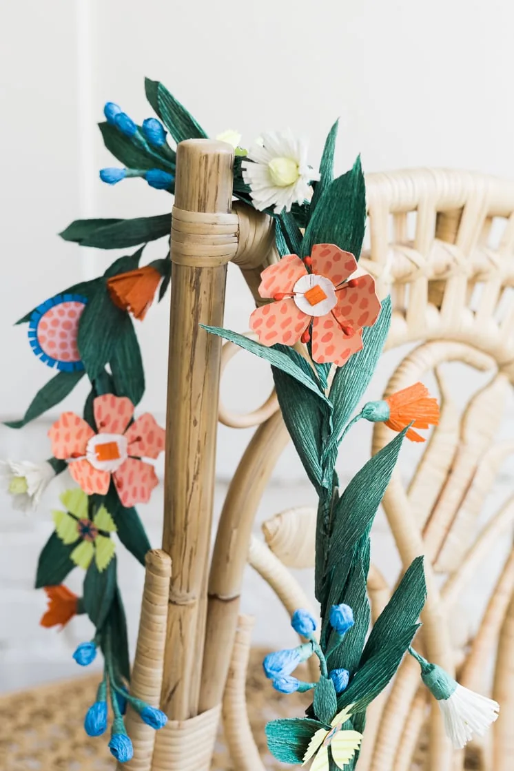 Paper flower garland hangs over a rattan chair
