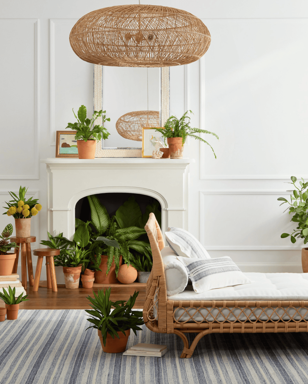 A rattan day bed in an airy room full of plants in terracotta planters