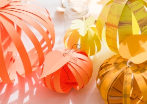 orange, gold, and yellow paper pumpkins on a table setting.