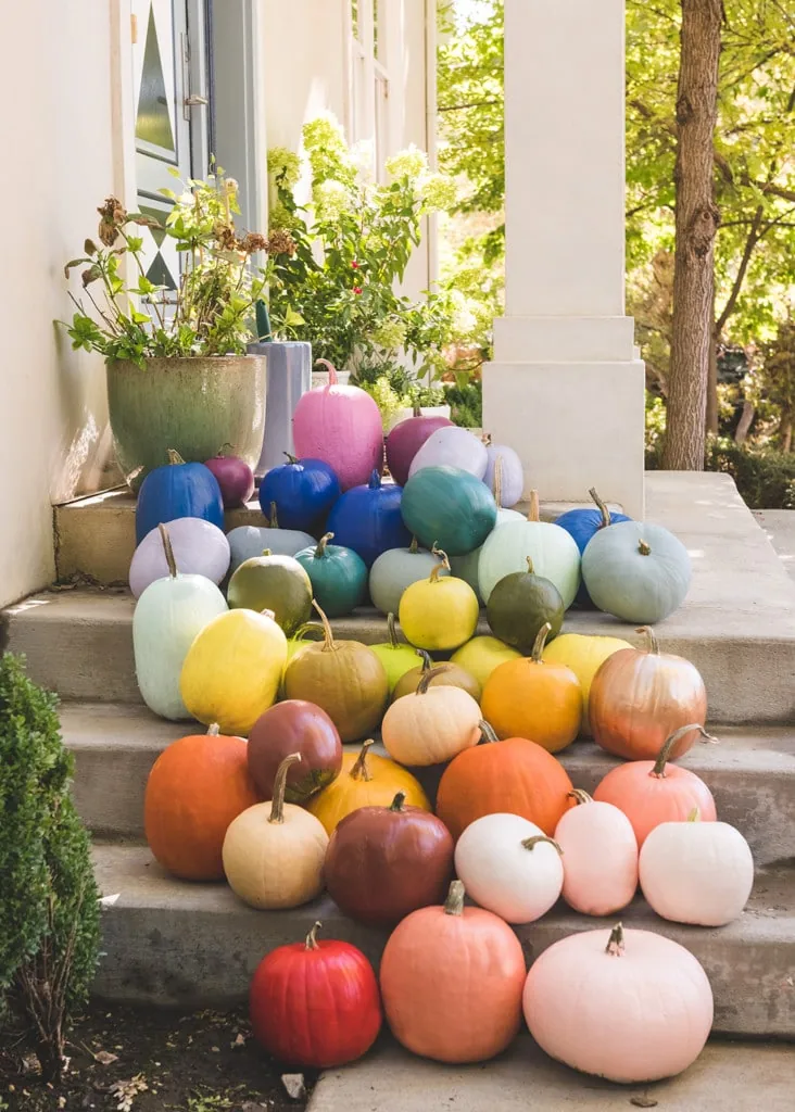 Rainbow pumpkins arranged on a porch.
