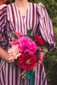 Paper peony bouquet held by a person in a striped dress