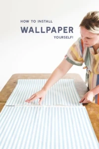 Brittany works on installing blue and white striped wallpaper with text that reads "how to install wallpaper yourself"