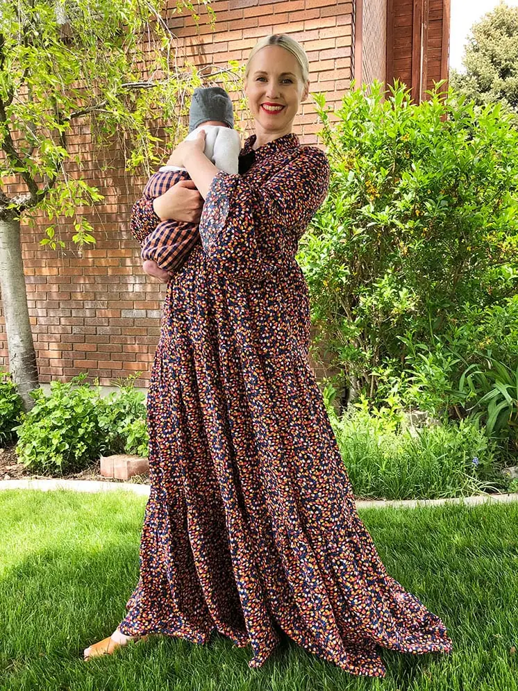 Brittany wearing a long floral dress and holding a baby