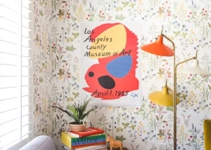 A colorful lamp in a room with wildflower wallpaper and a LACMA exhibition poster