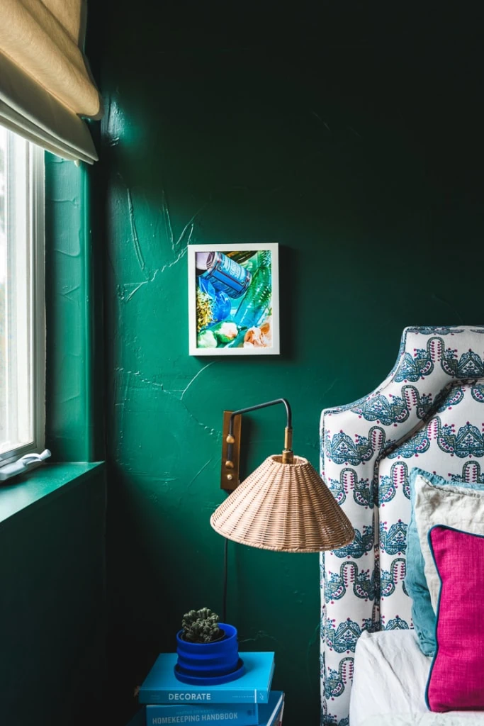 a chaunte vaughn photo hanging against a textured green wall above a lamp by a headboard.