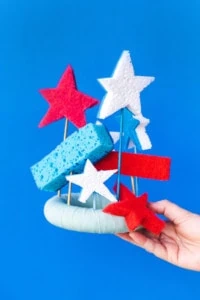 Red white and blue sponges attached to a DIY sponge crown on a blue background.