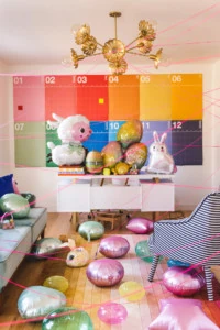 Interior Photo of a colorful room with Easter-themed balloons on the desk and floor, and pink string criss-crossing through the space.