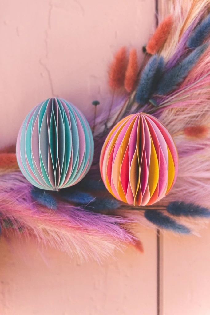 Paper honeycomb Easter Eggs on a pastel floral wreath against a pink wall