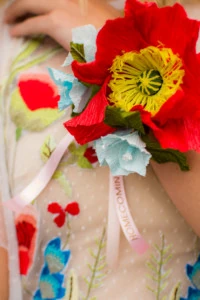 a brightly colored paper poppy corsage