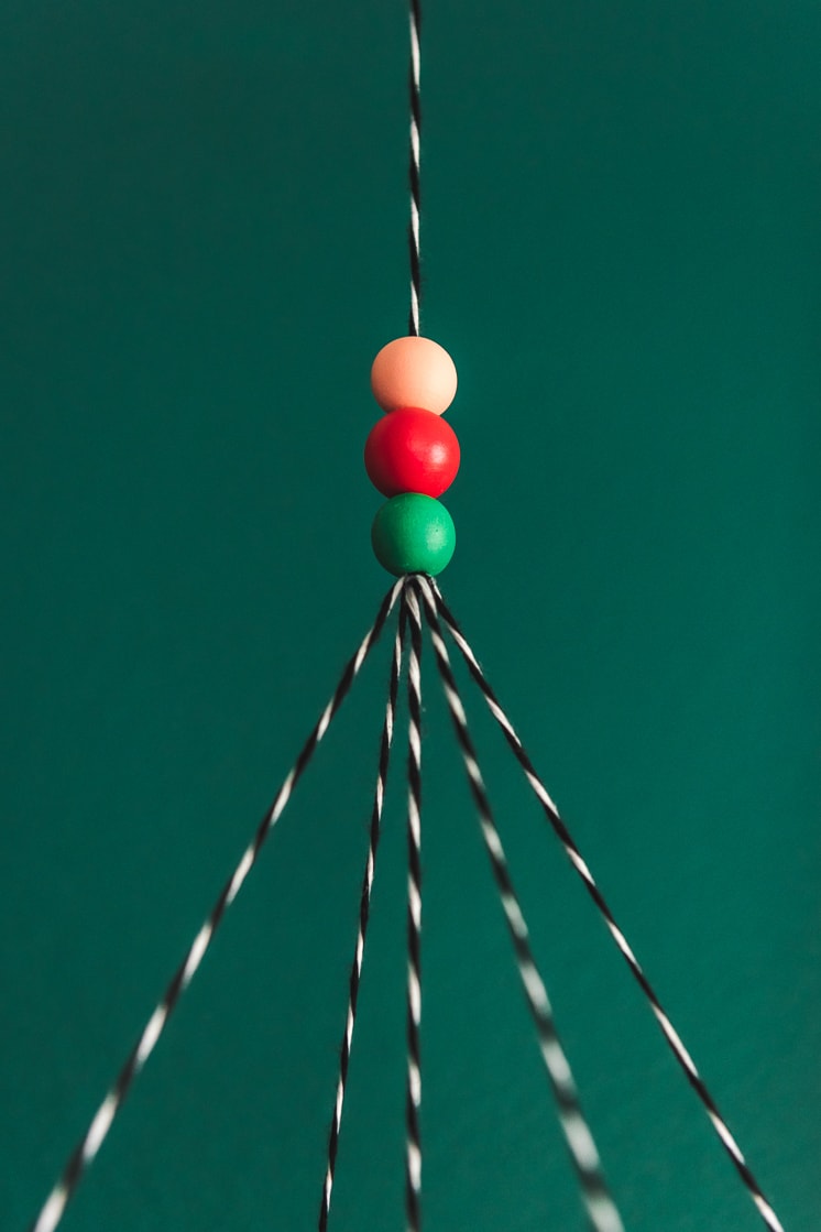 Painted wooden beads on black and white string against a green wall