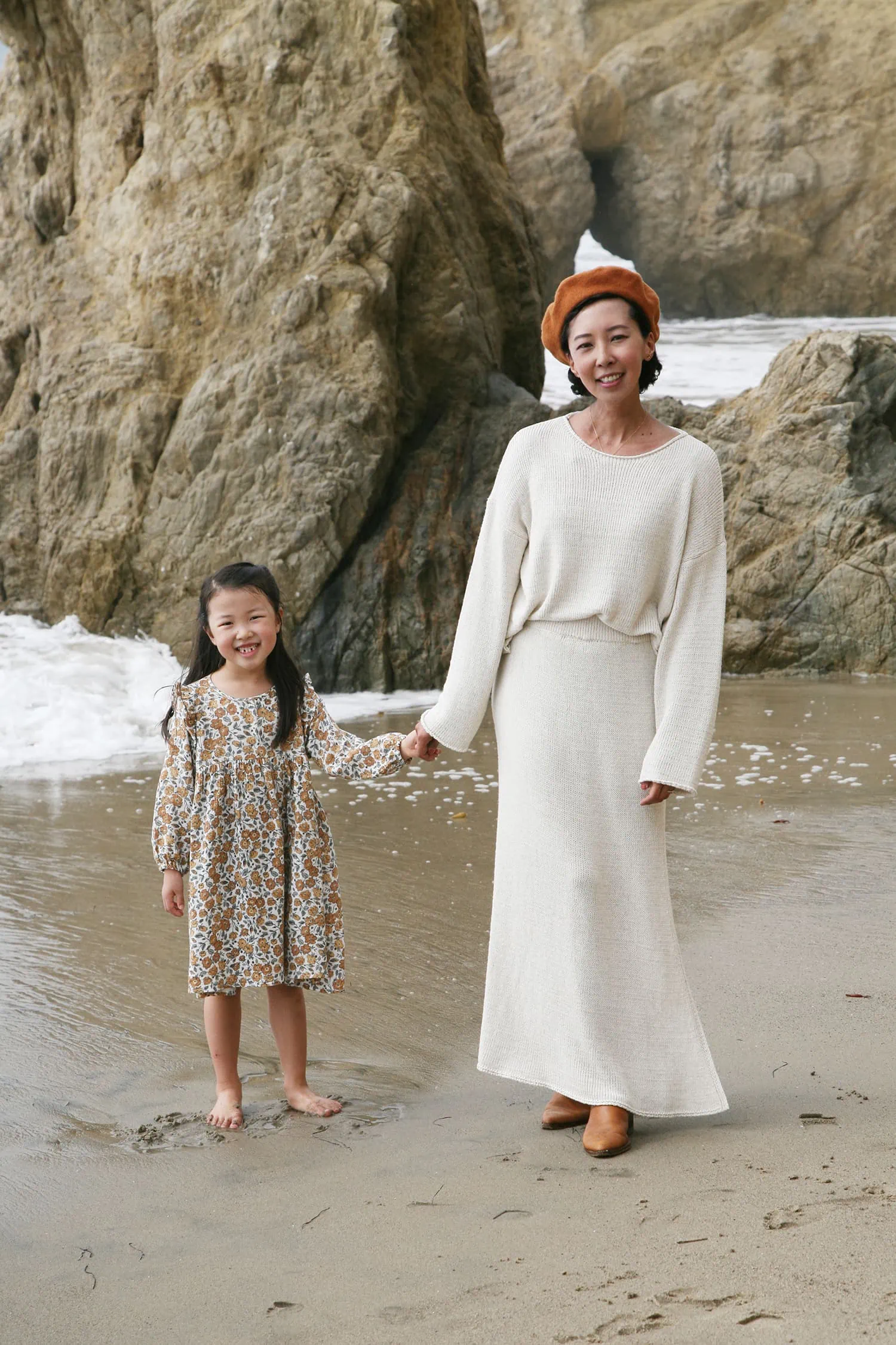 Jeanee and her daughter are standing on a beach. They're holding hands and smiling at the camera.