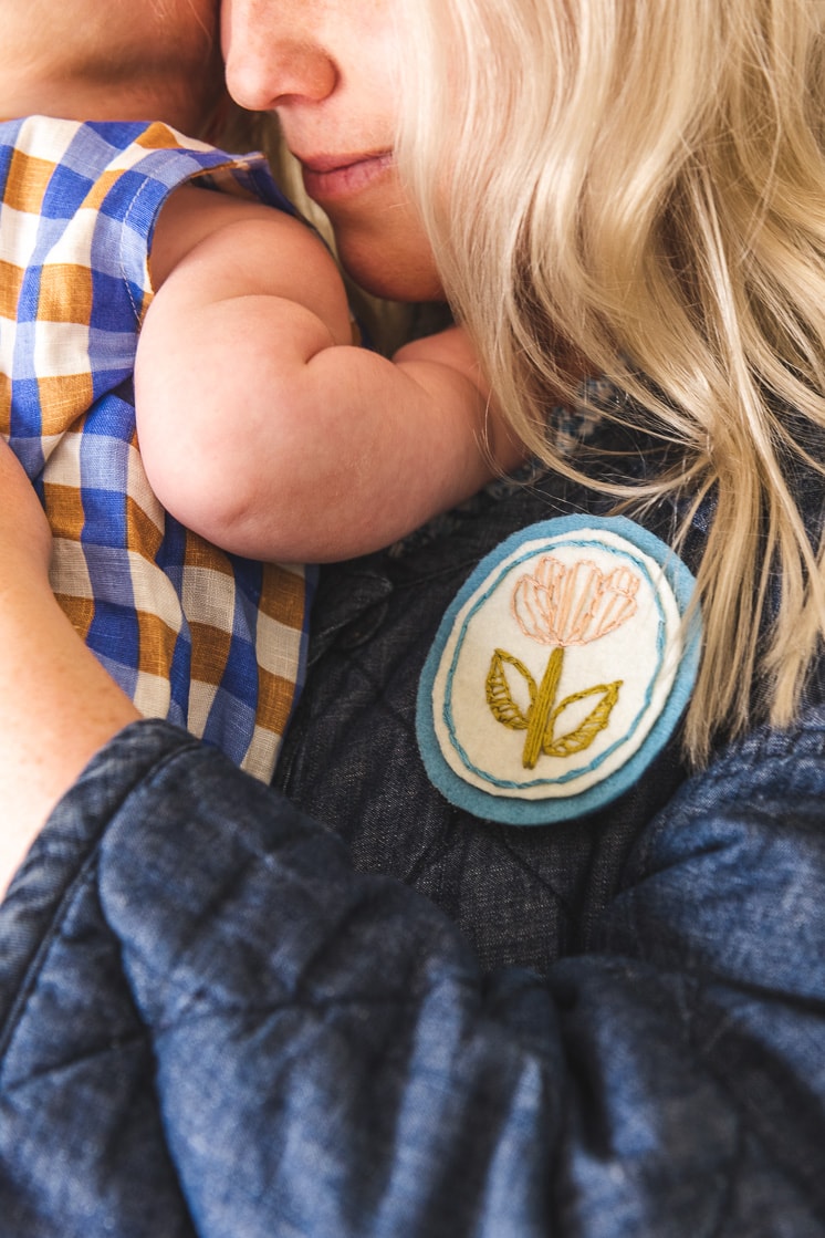 Brittany is sporting her embroidered floral brooch and holding baby Felix.