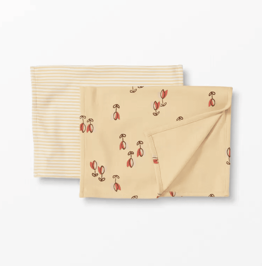 Two burp cloths on a white background. One is yellow and white striped and one is yellow with little red tulips.