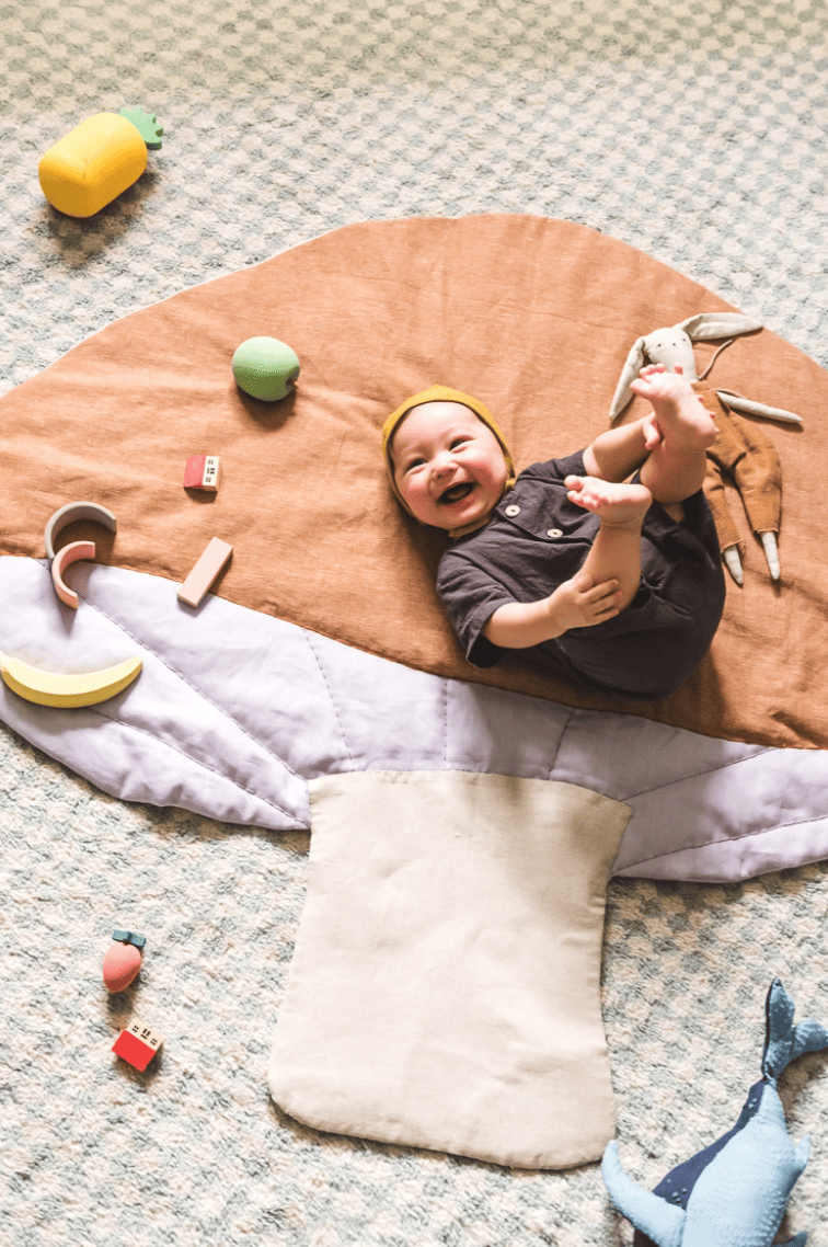 Happy baby lying on a mushroom playmat
