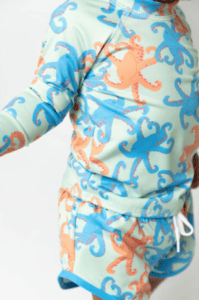 a matching rashguard and swim trunk set featuring range and blue octopuses on a mint green background.