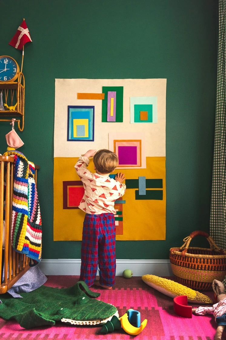 Jasper in a colorful room. He's playing with a colorful felt board made of bright squares and rectangles