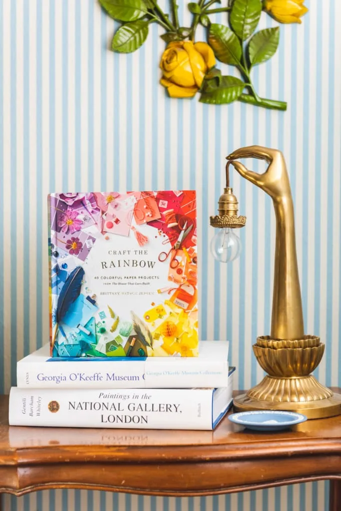 Craft the Rainbow book on a table with a brass hand-shaped lamp against a striped wall.