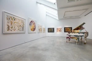 Installation shot of large botanical floral prints and a botanical wrapped piano in a gallery