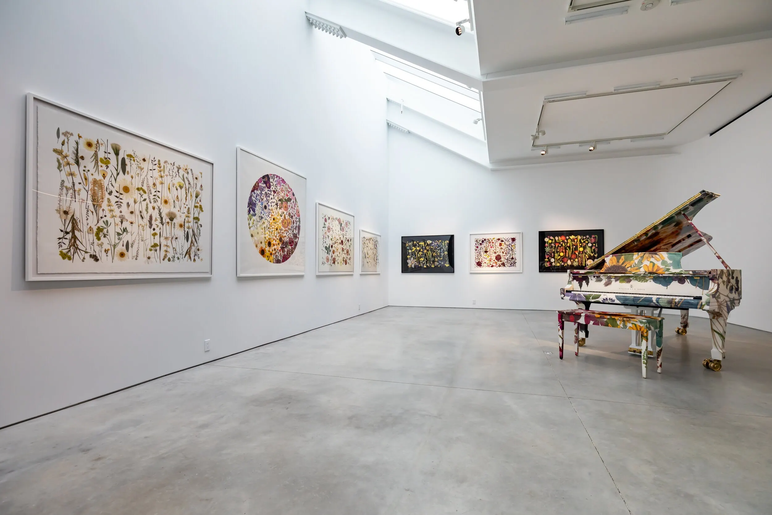 Installation shot of large botanical floral prints and a botanical wrapped piano in a gallery