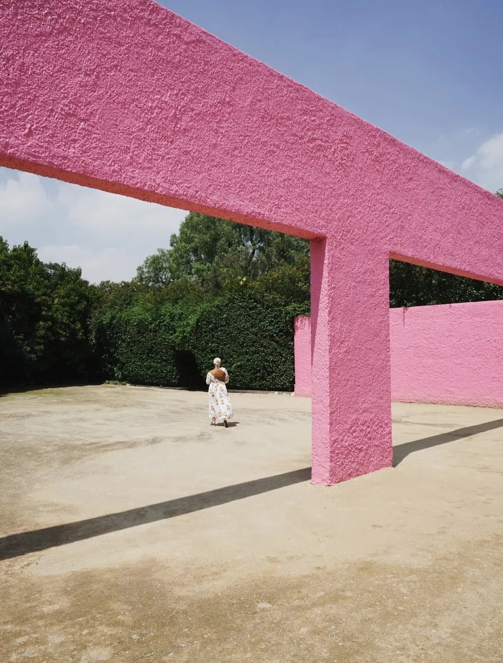 Brittany walks under a bright pink structure at Luis Barragán's San Cristobal stables in Mexico City