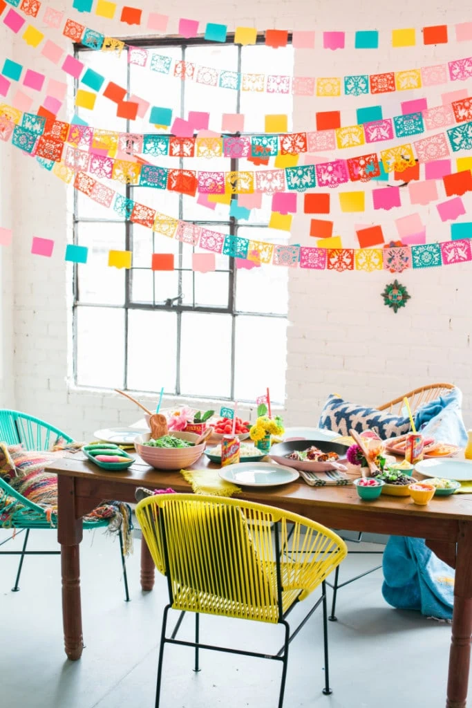 a festive Cinco de Mayo table set with Mexican food and decorated with colorful papel picado banners