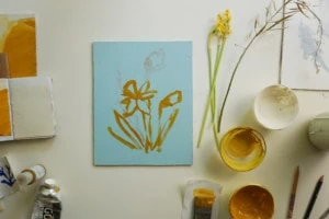 A styled shot of Rachel Smith's Daffodil I print in progress with paint pots and papers around it.