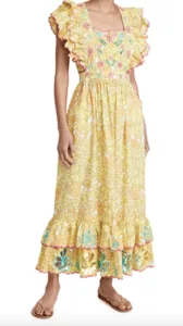 A woman wears a light yellow floral dress with Mexican-inspired embroidery and frilled sleeves with a flounce at the bottom.
