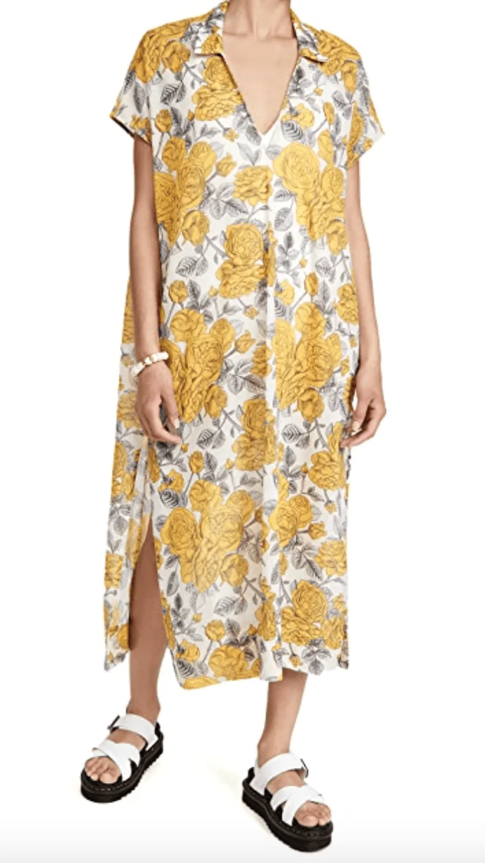 A woman wears a loose maxi dress in a shirt dress pattern. It's printed with large yellow flowers.