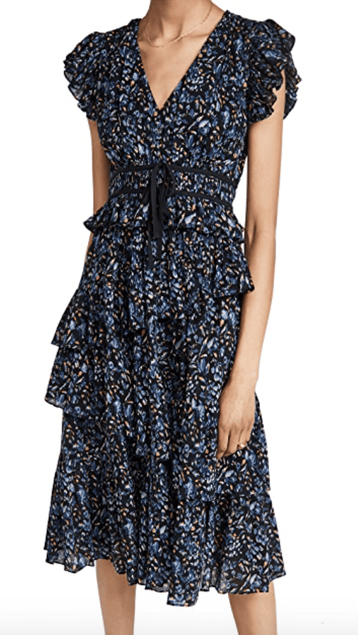 A blue calico-printed midi dress with ruffles and flounces crossing the body and on the short sleeves. It has a tied belt and a v neck
