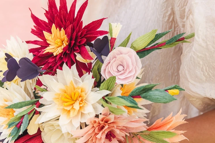 close up of a paper bouquet made of dahlias, roses, shamrocks, Mexican jasmine, and foliage.