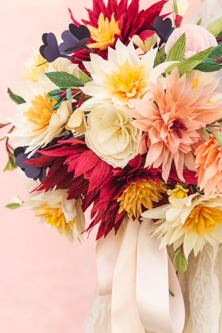close up of a paper bouquet made of dahlias, roses, shamrocks, Mexican jasmine, and foliage.
