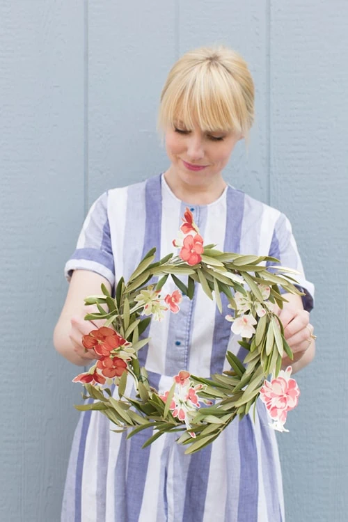 Brittany holding a wreath with floral accents cut from wallpaper.