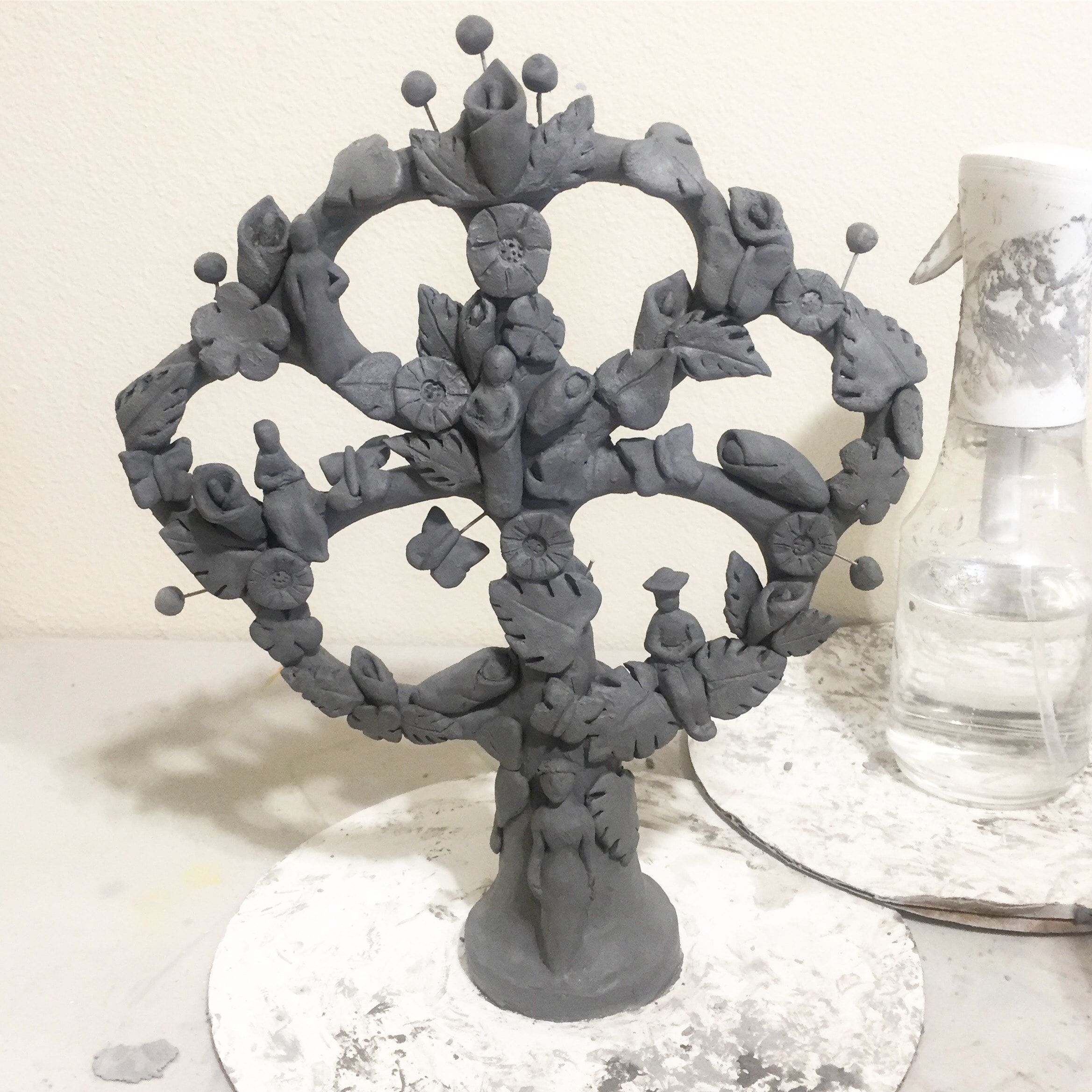 A clay sculpture featuring lots of flowers and plants.