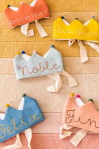 flower lane crowns in orange, yellow, pink, blue, and light blue on a yellow and pink background.