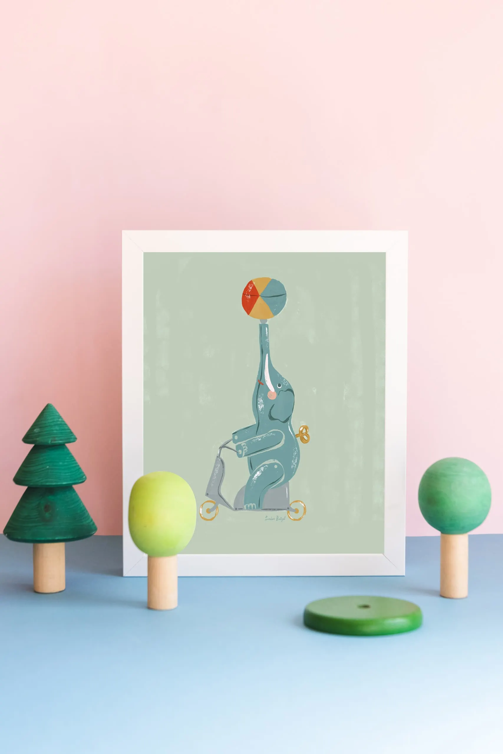 A print of Louise Pretzel's elephant leans against a pink wall with wooden tree toys in front of it.