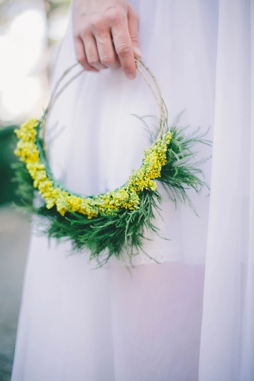 Goldenrod flower crown from Midsummer Mingle. A woman in a white dress holds it against her side. 