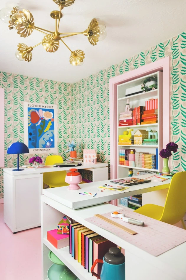 Interior shot of the finished office. The wallpaper is up, the doorframes are painted pink, there's a blue art print with colorful flowers on the wall, and yellow chairs are in the desks. It's vibrant, light-filled, and fun. 