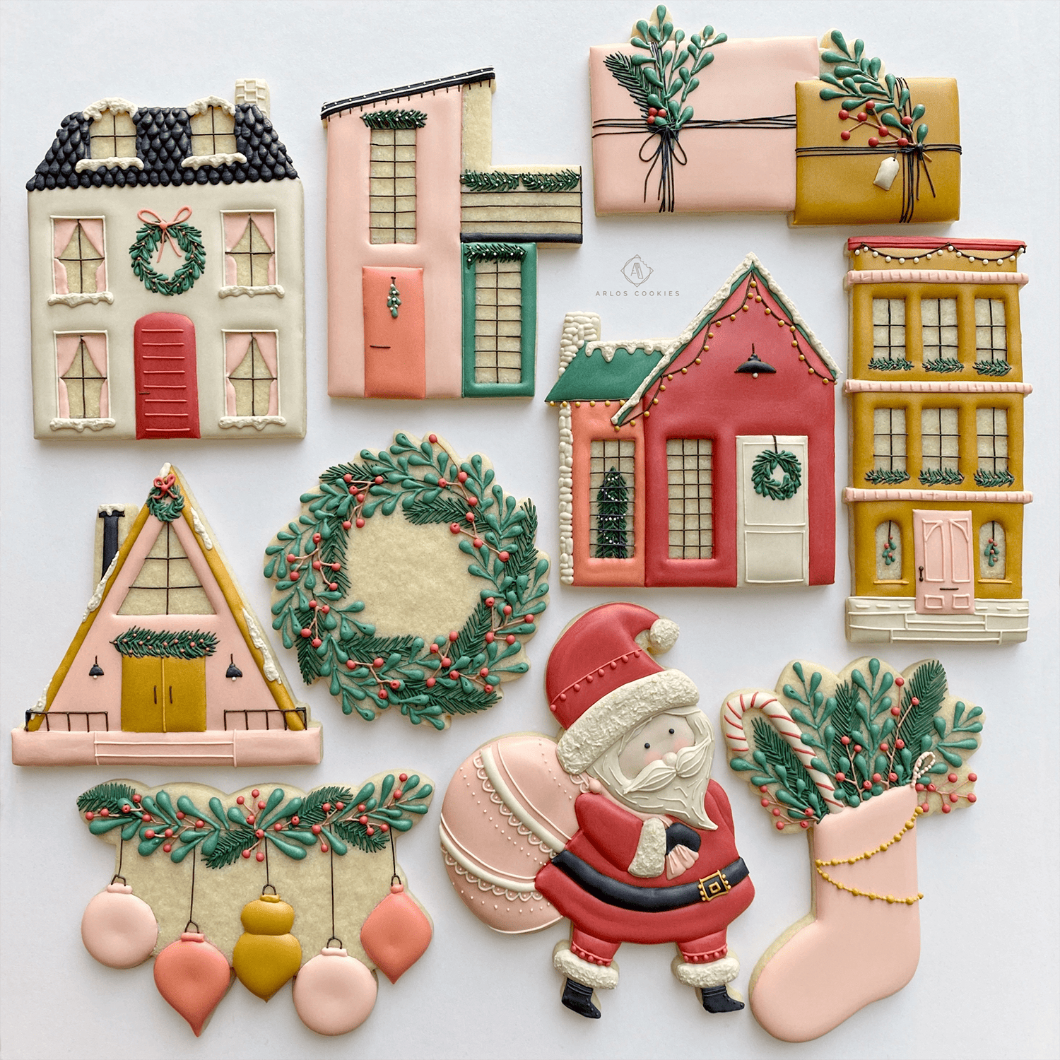 Christmas-themed decorated cookies. They're shaped like houses, presents, a wreath, a stocking, Santa Claus, and ornaments.
