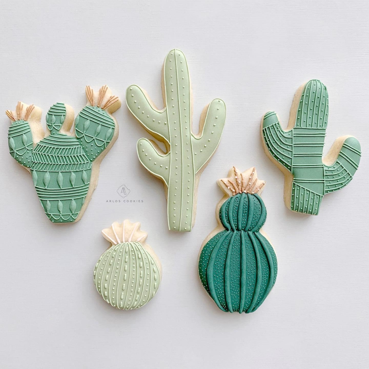 Five cactus-shaped cookies in various shades of green.