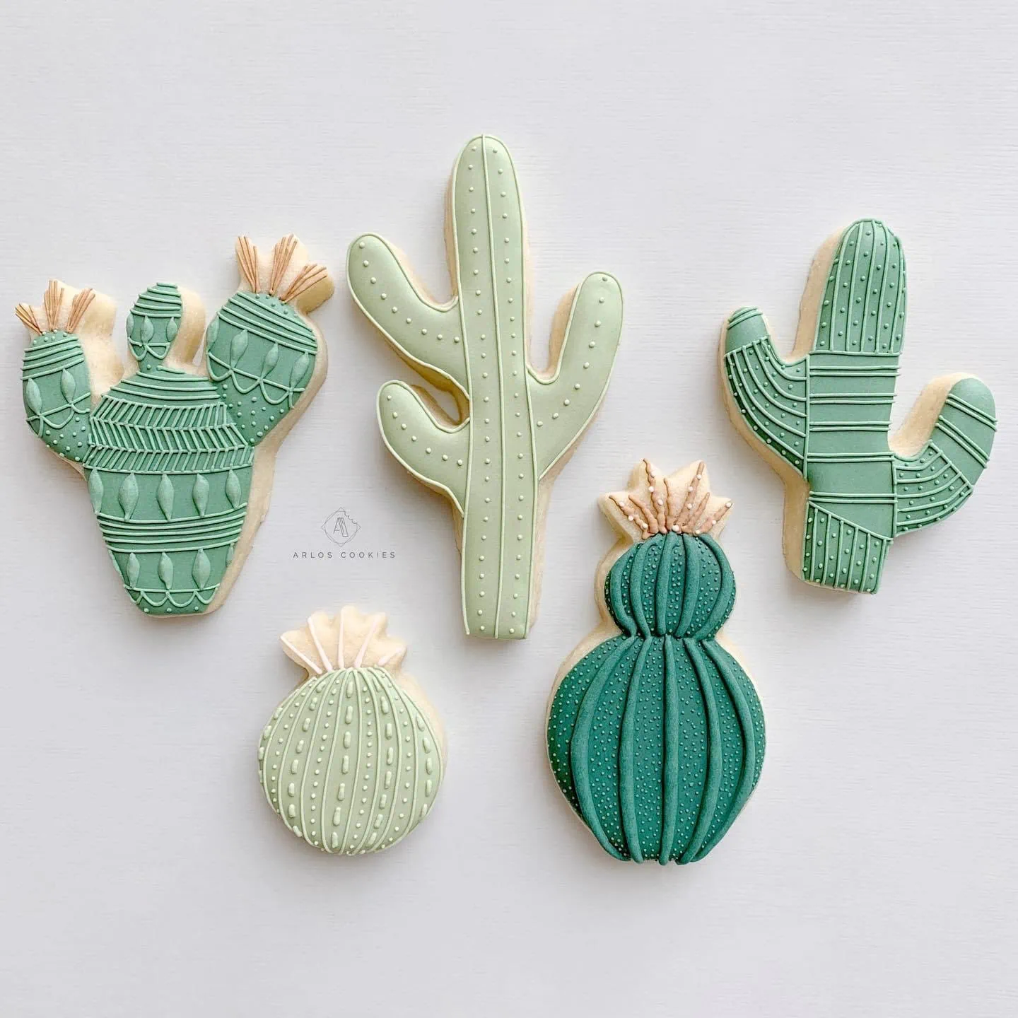 Five cactus-shaped cookies in various shades of green.