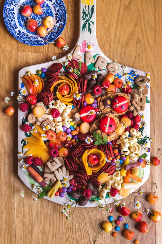 a painted charcuterie board loaded with colorful snacks.