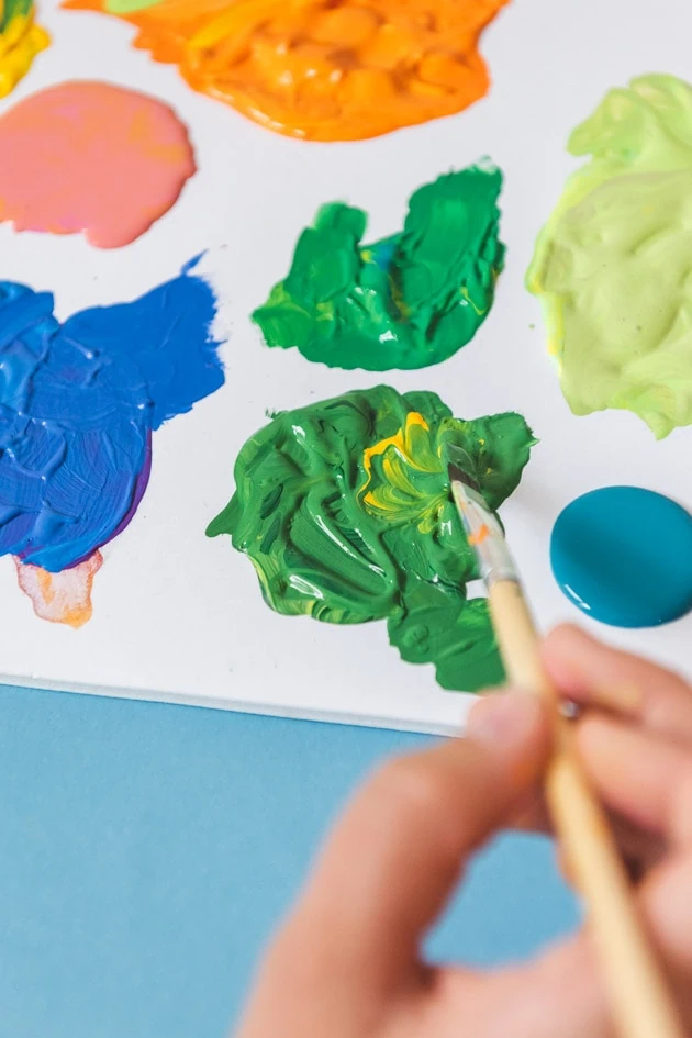 mixing different colors of green, blue, pink, and orange paint.