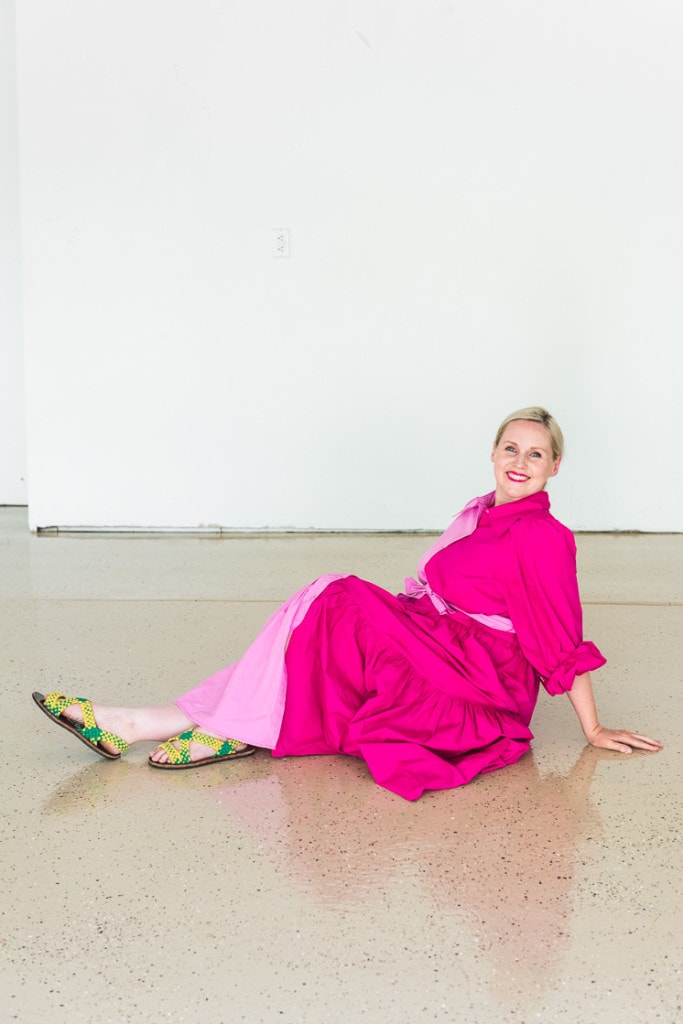 Brittany sits on her epoxied garage floor wearing a two-toned pink dress.