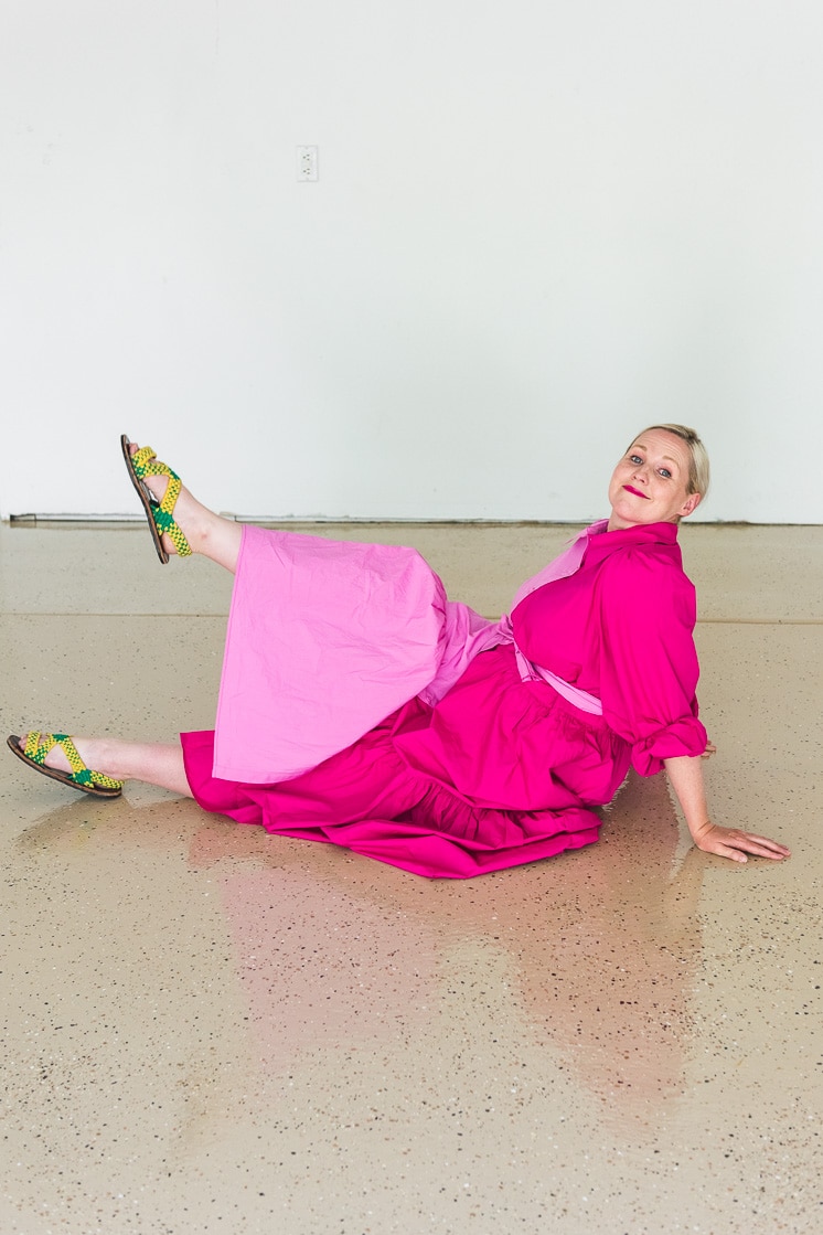Brittany lies down on the epoxy floor wearing a two-toned pink dress.