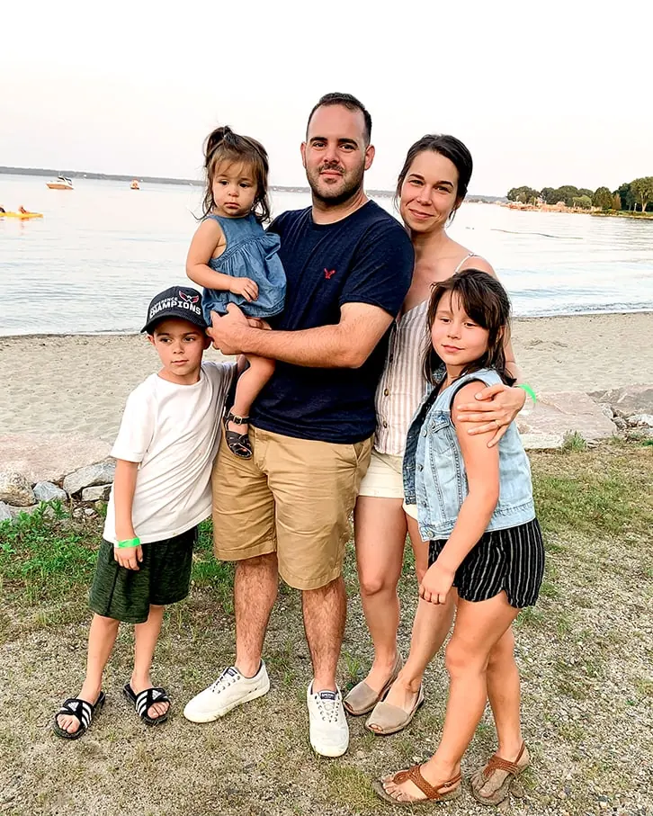 Sarah Cambio, her husband, and her three kids standing by a beach and smiling at the camera.