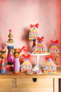 Colorful cookie boxes arranged next to a handpainted midcentury nativity against a pink wall